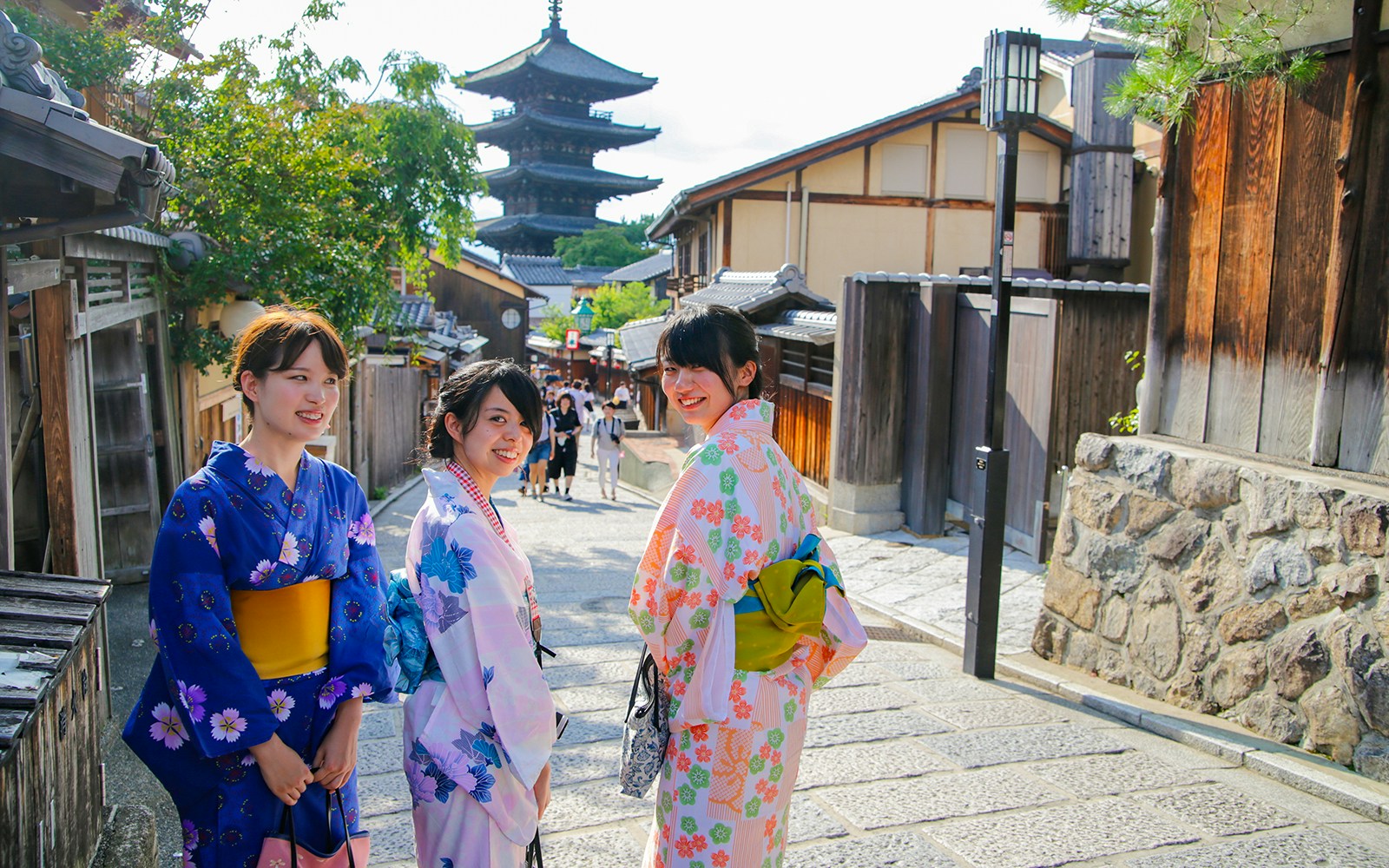 Women in kimonos walking in historic Kyoto street with Yasaka Pagoda in the background.