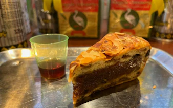 Pastry slice with almonds and a small cup of liqueur on a tray during The Hague food tour.