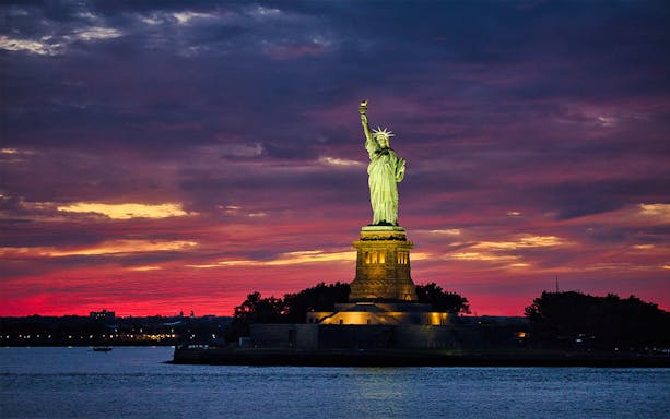 Statue of Liberty illuminated at sunset, New York City.