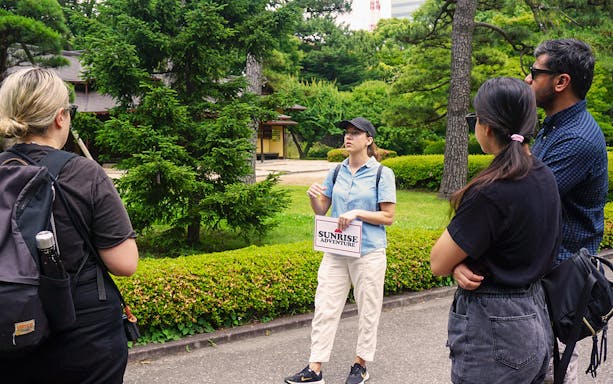 Tour guide leading a group through the gardens of Tokyo's Imperial Palace.