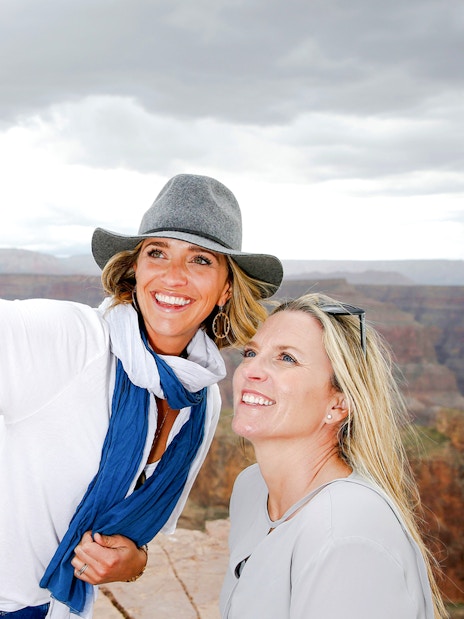 Two women taking a selfie at the Grand Canyon Skywalk with canyon view.