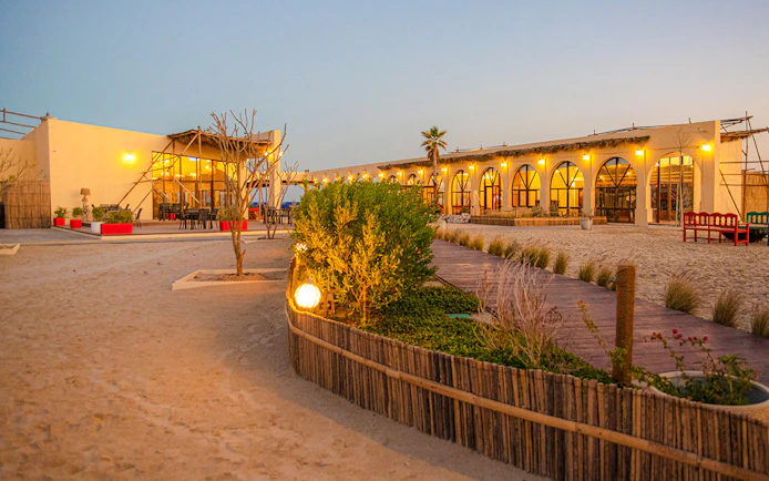 Al Majles Resort courtyard with lit pathways and arched windows at dusk.