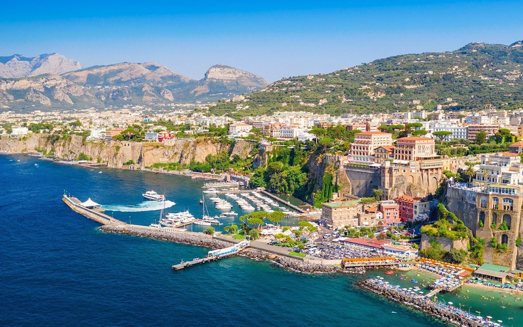 Cetara harbor on the Amalfi Coast with boats docked and colorful buildings on cliffs.
