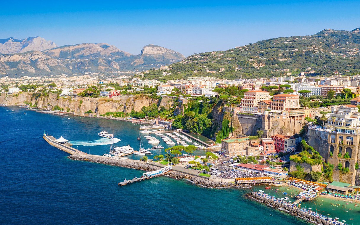 Cetara harbor on the Amalfi Coast with boats docked and colorful buildings on cliffs.