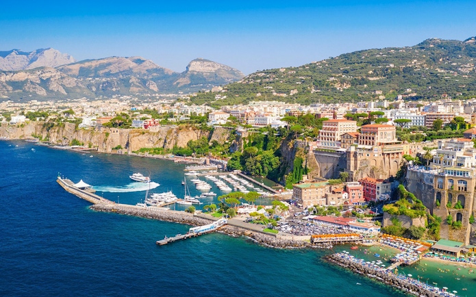 Cetara harbor on the Amalfi Coast with boats docked and colorful buildings on cliffs.
