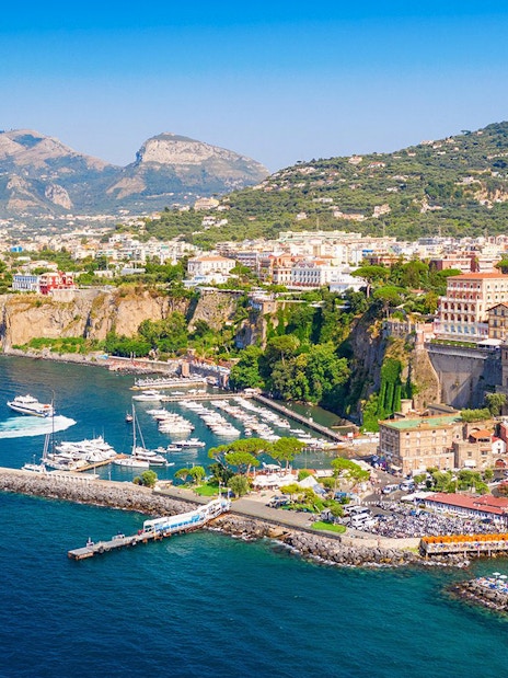 Cetara harbor on the Amalfi Coast with boats docked and colorful buildings on cliffs.