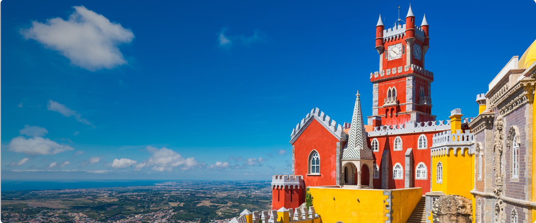 Pena Palace in Sintra with vibrant red and yellow towers against a clear blue sky.