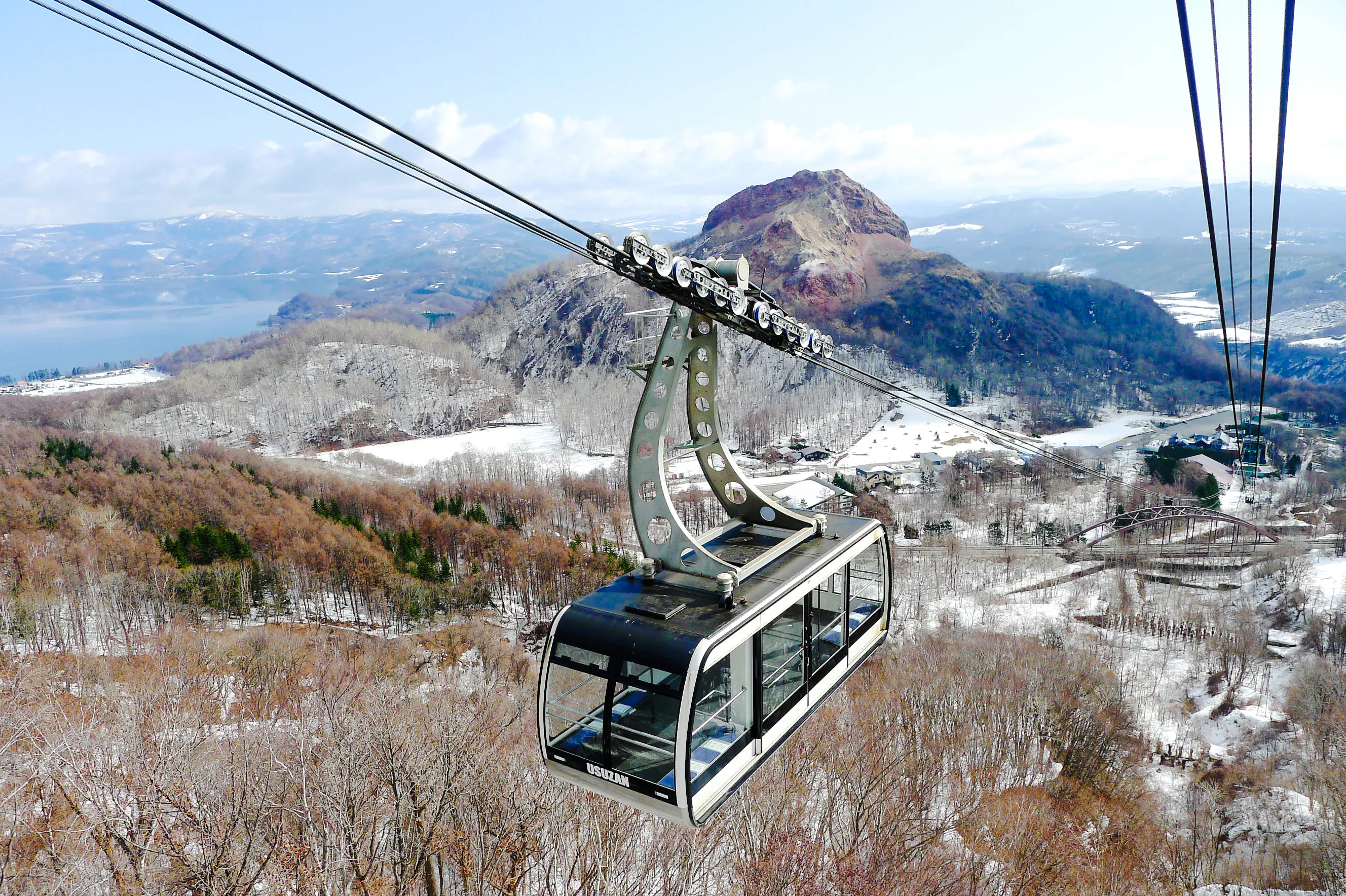 Cable car over snowy landscape with Lake Toya and Mount Usu in Hokkaido, Japan.