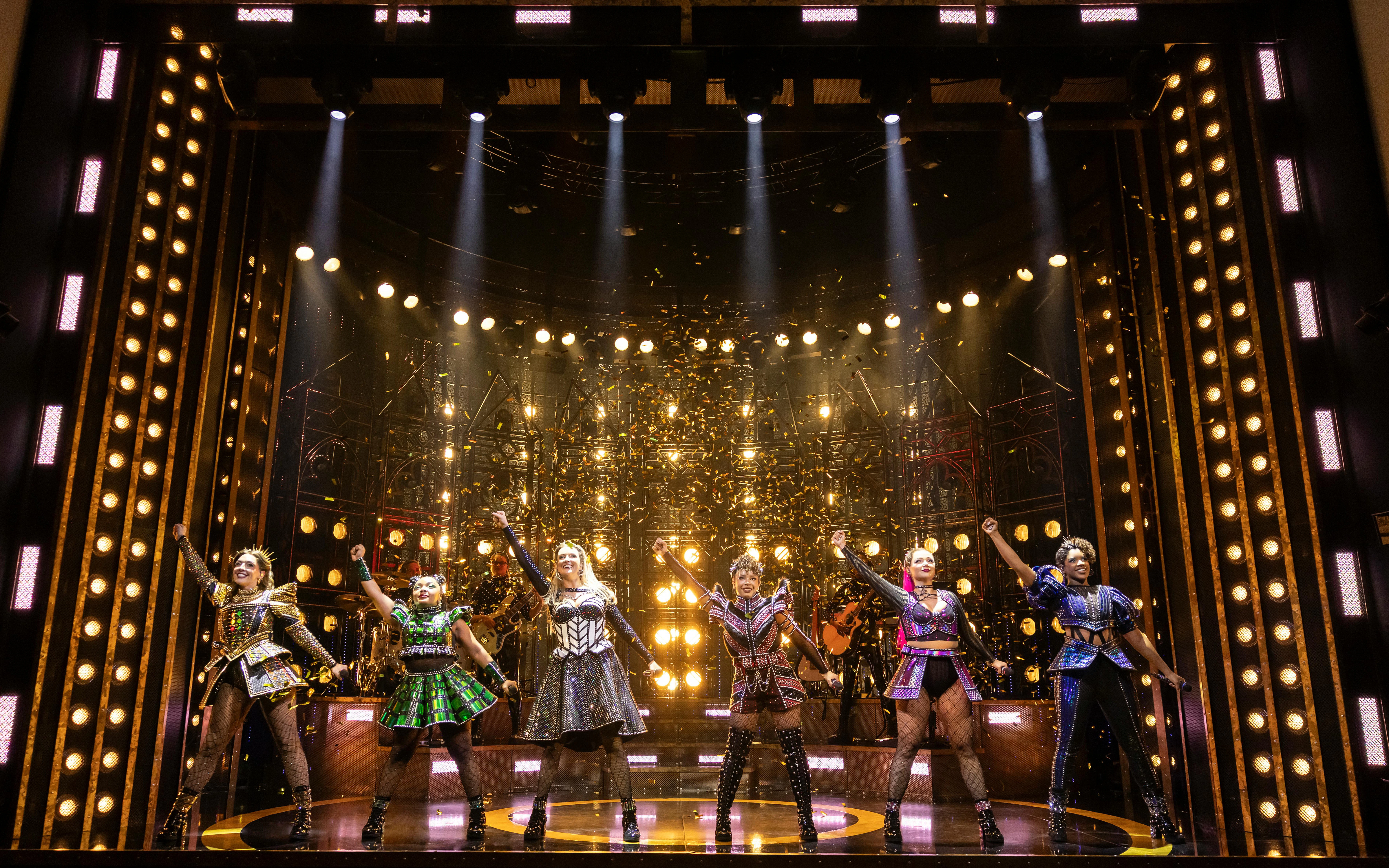 Six musical cast performing on stage at West End theater.