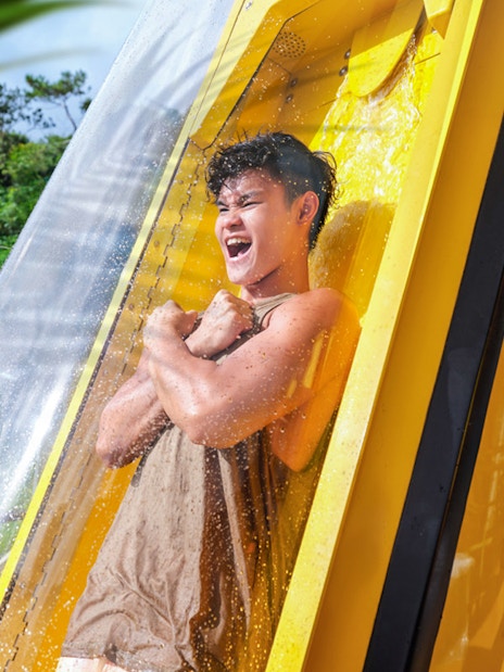 Person enjoying a water slide at Ocean Park with lush greenery in the background.