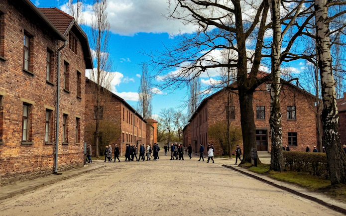 Visitors walking between brick barracks at Auschwitz I camp in Oświęcim, Poland.