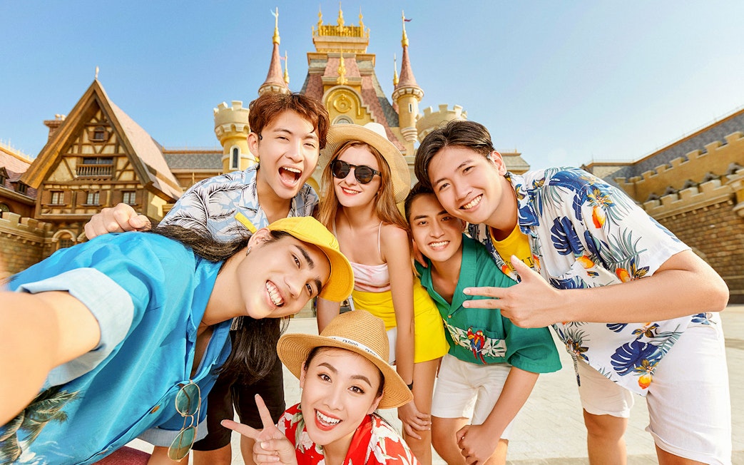 Guests smiling at Vinwonders entrance with castle backdrop.