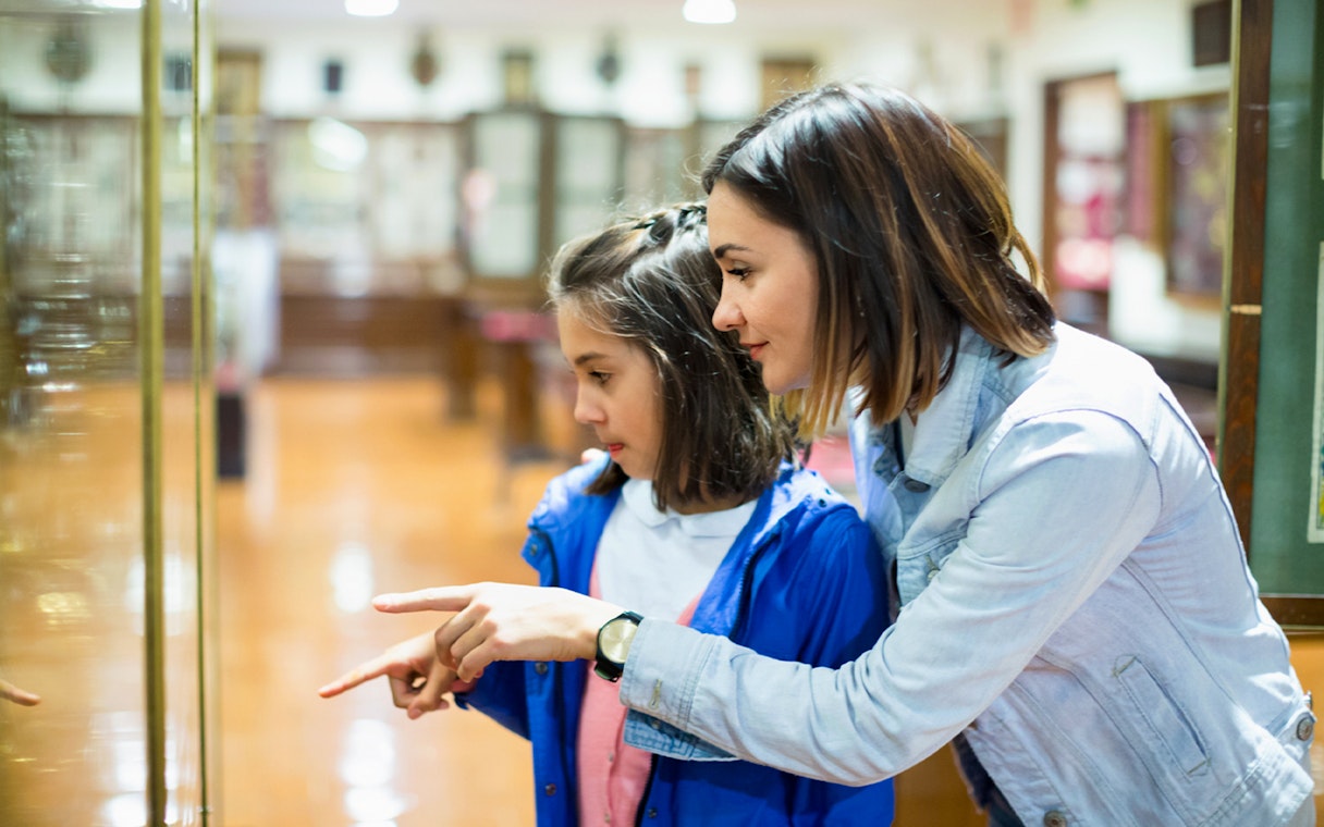 Mother and daughter pointing at museum artifact display.