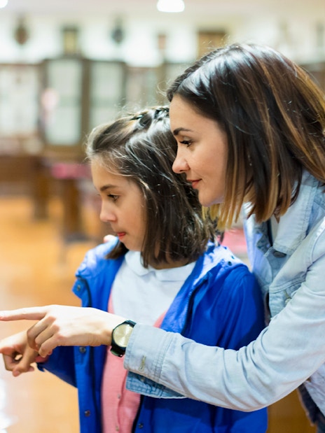 Mother and daughter pointing at museum artifact display.