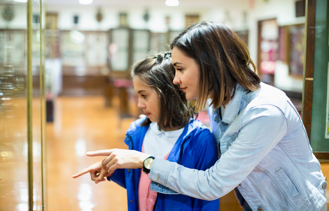 Mother and daughter pointing at museum artifact display.