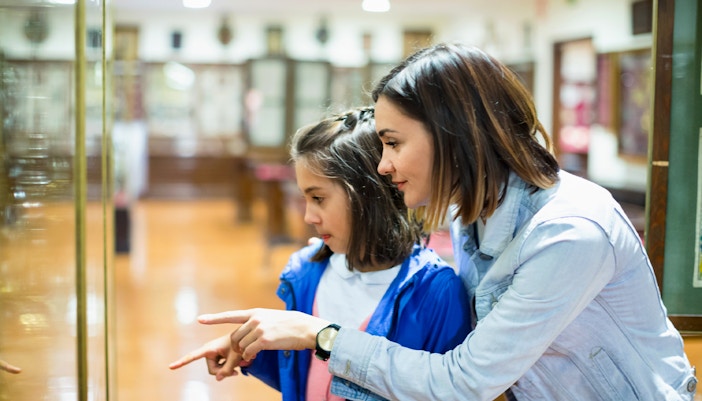 Mother and daughter pointing at museum artifact display.