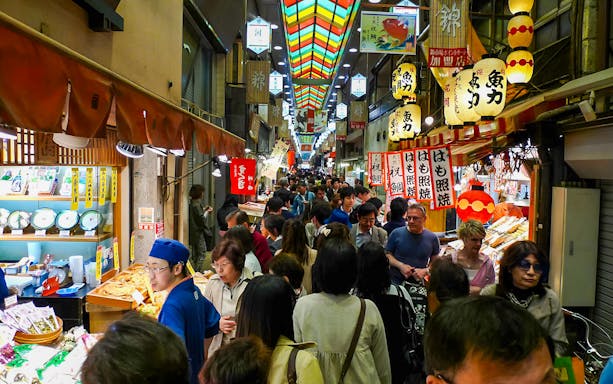 Crowded Kyoto Nishiki Market with people exploring food stalls.