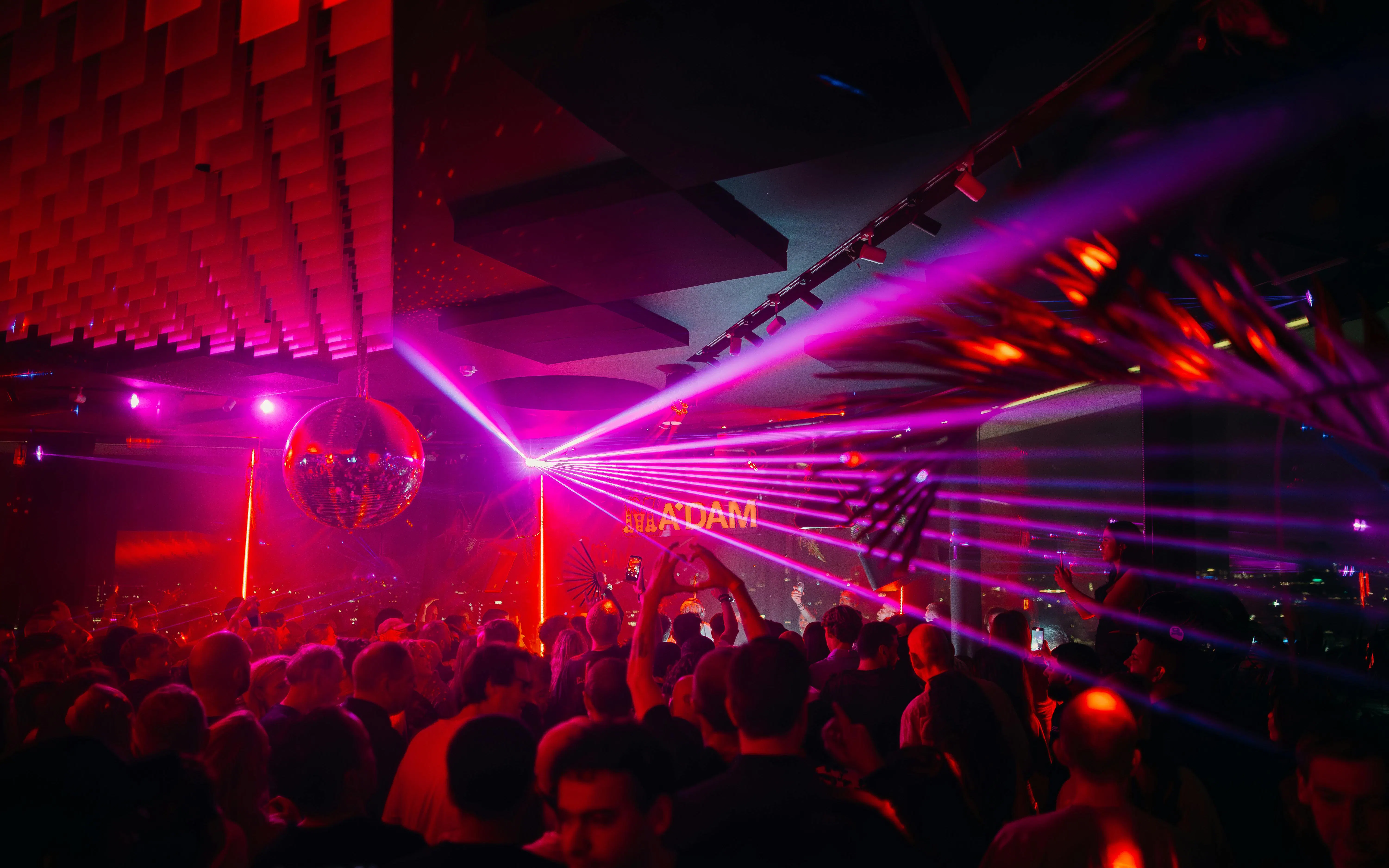 Crowd enjoying nightlife with laser lights at A'DAM Tower Skybar, Amsterdam.