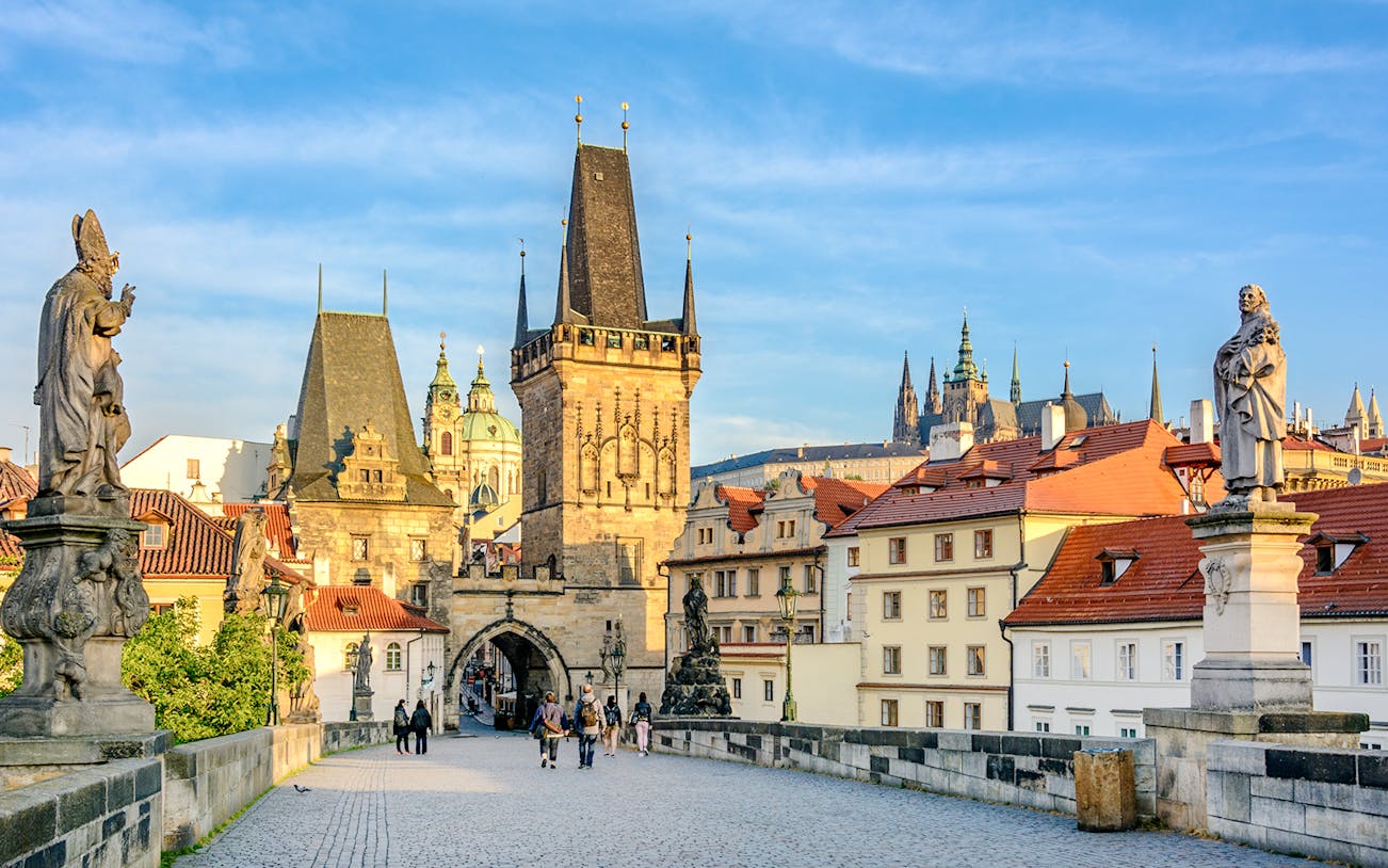 Charles Bridge in Prague with statues and Gothic towers in the background.