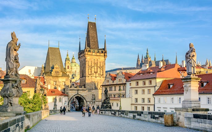 Charles Bridge in Prague with statues and Gothic towers in the background.