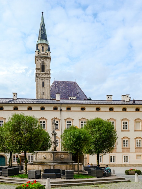 St. Peter monastery courtyard with fountain and tower in Salzburg, Austria.