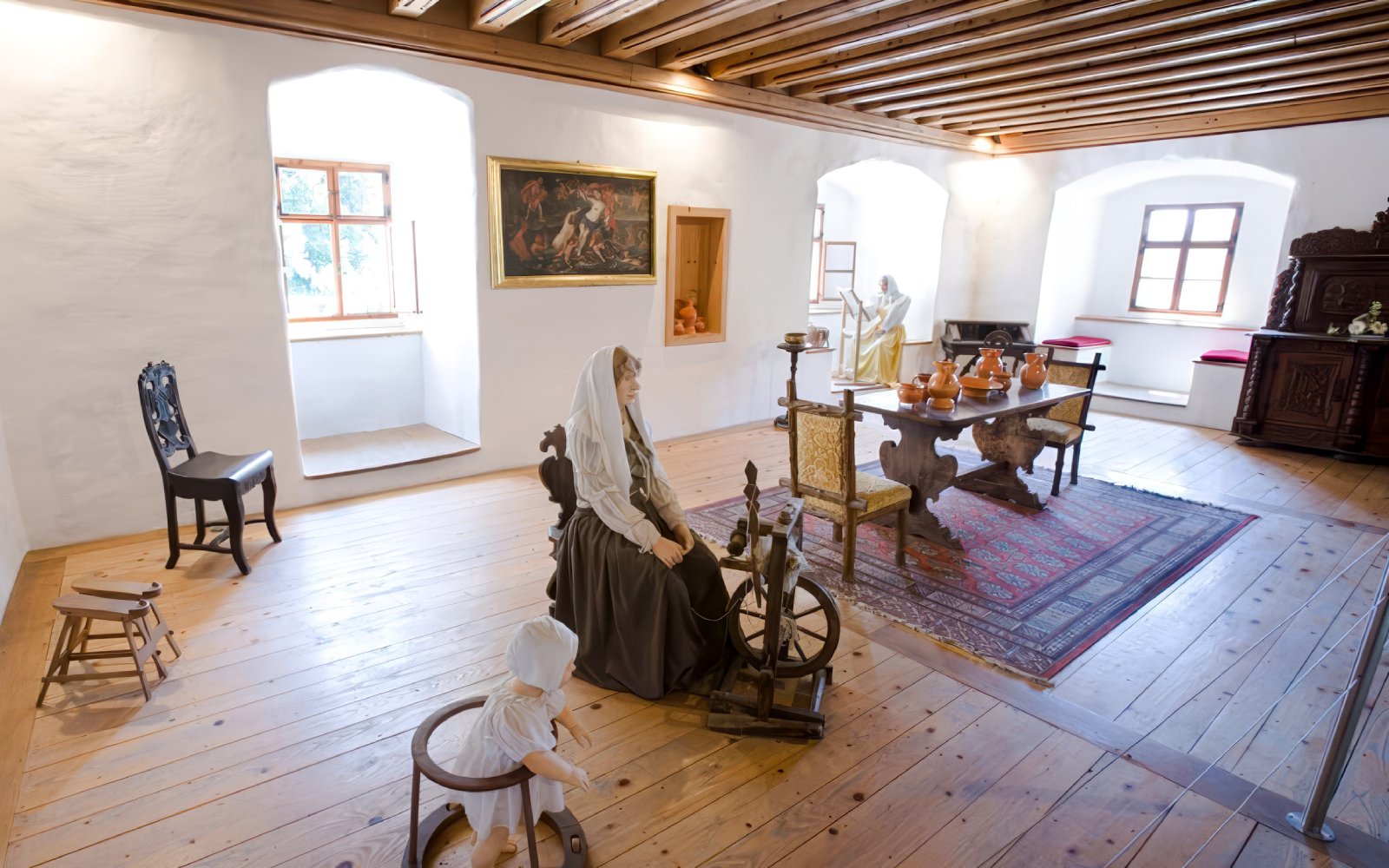 Interior of Predjama Castle with historical furnishings and mannequins depicting medieval life.