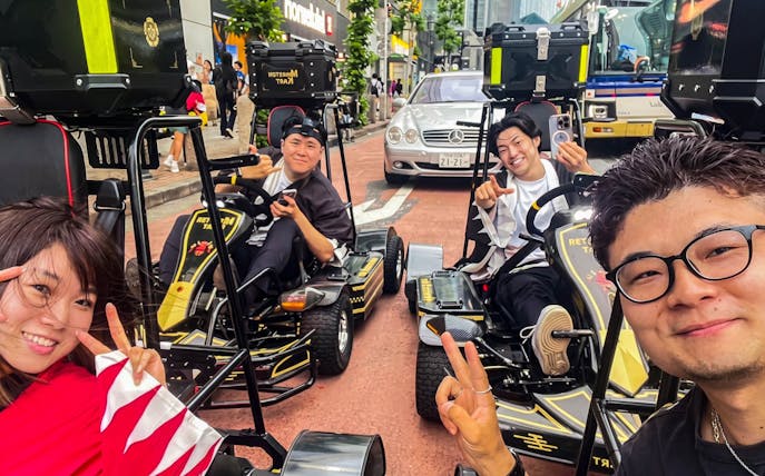 People enjoying a street kart experience in Tokyo, posing with peace signs on a busy city street.