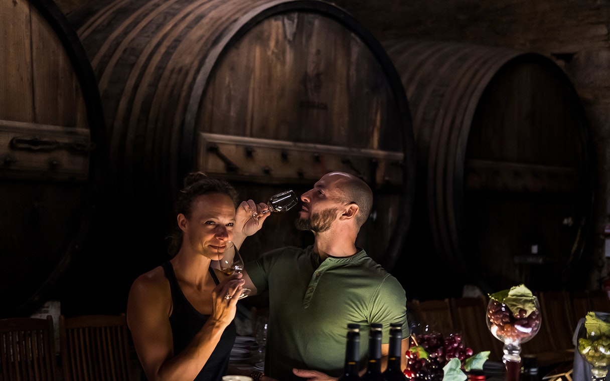 Wine tasting in a Porto cellar with large wooden barrels in the background.