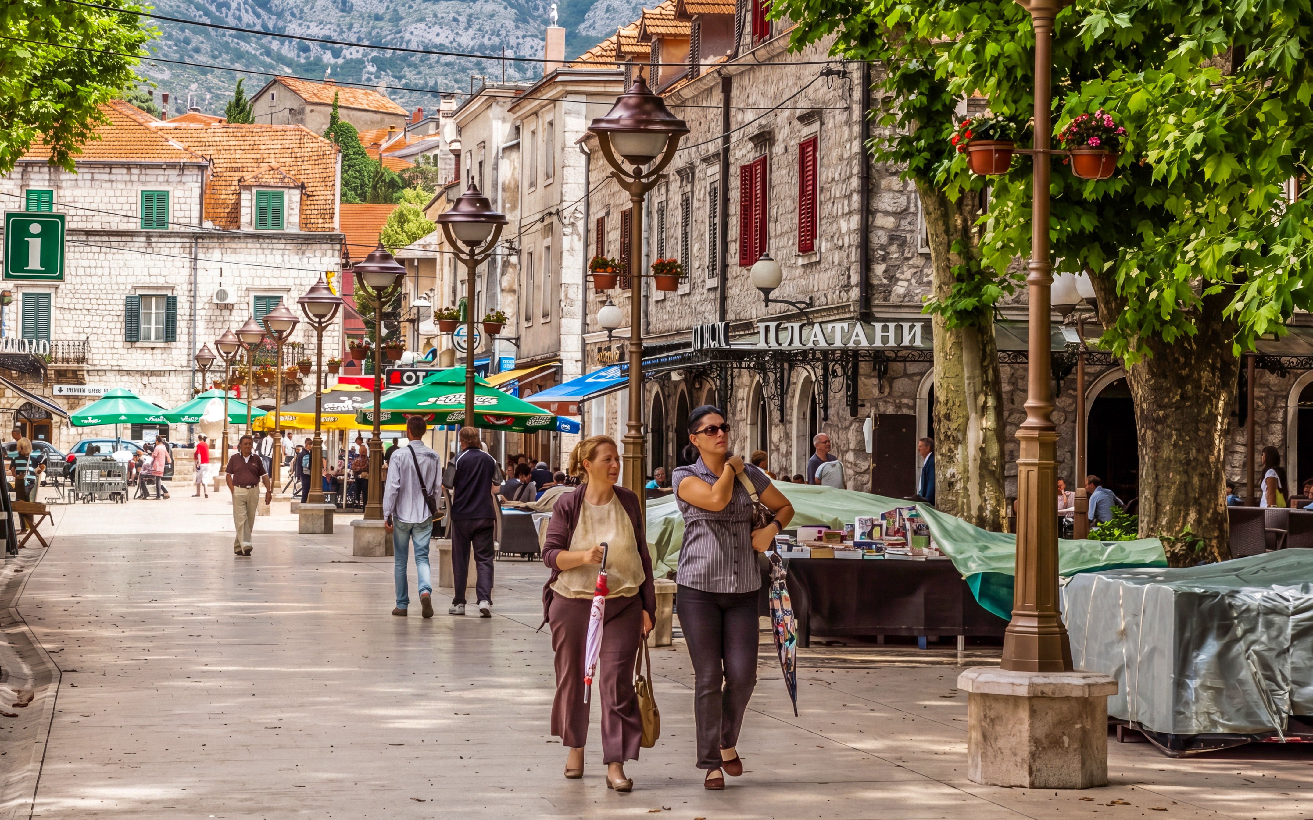 Pedestrian street in Trebinje, Bosnia and Herzegovina, with cafes and people walking.
