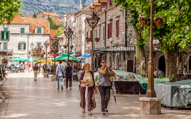 Pedestrian street in Trebinje, Bosnia and Herzegovina, with cafes and people walking.
