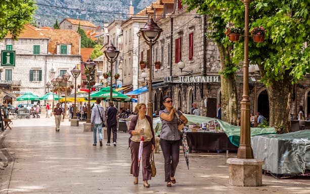 Pedestrian street in Trebinje, Bosnia and Herzegovina, with cafes and people walking.