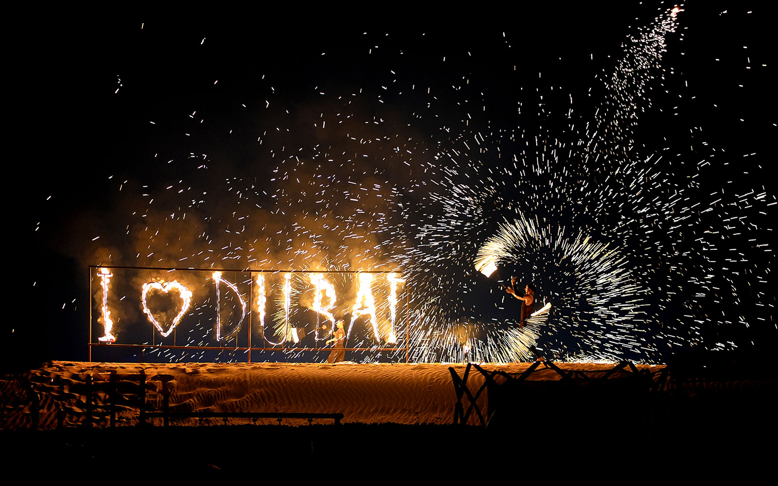 Fire performer with "I ♥ DUBAI" sign during evening desert safari.