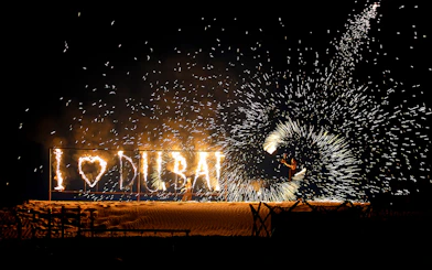 Fire performer with "I ♥ DUBAI" sign during evening desert safari.