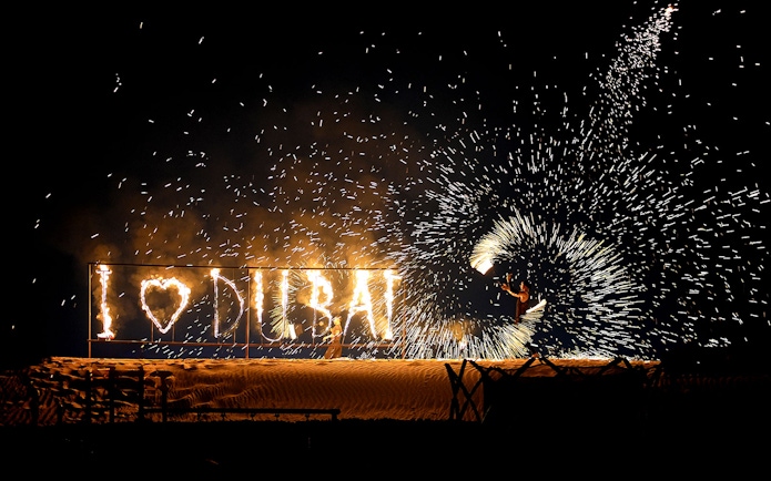 Fire performer with "I ♥ DUBAI" sign during evening desert safari.