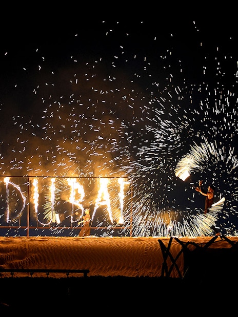 Fire performer with "I ♥ DUBAI" sign during evening desert safari.
