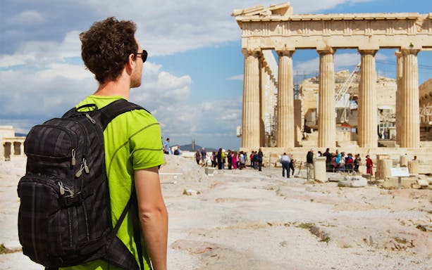 Tourist with backpack viewing the Parthenon at the Acropolis, Athens.