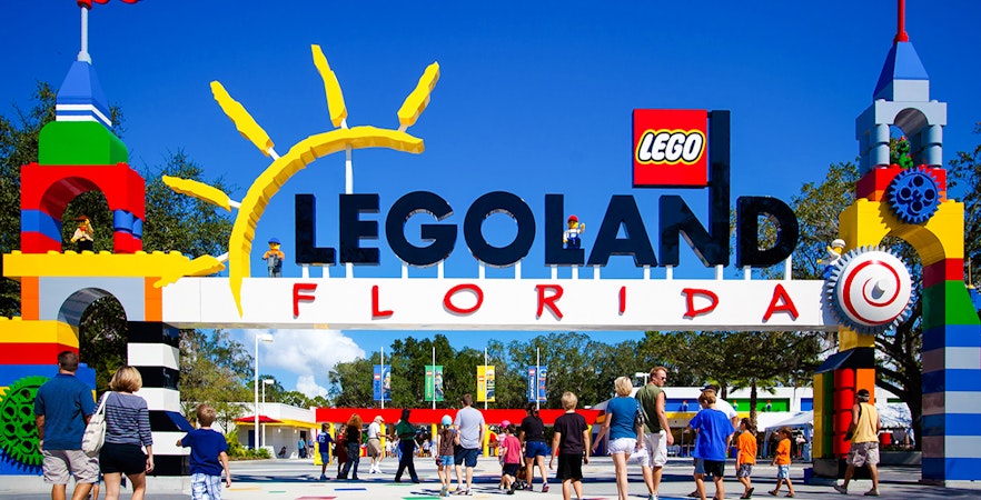 Entrance to Legoland Florida with colorful Lego structures and visitors walking in.