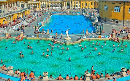 Outdoor pool at Széchenyi Thermal Bath, Budapest, with people swimming and relaxing.