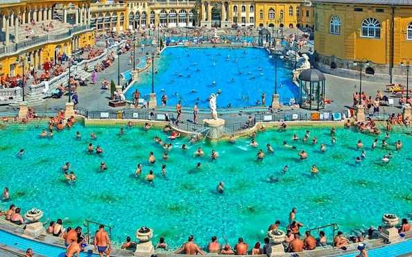Outdoor pool at Széchenyi Thermal Bath, Budapest, with people swimming and relaxing.