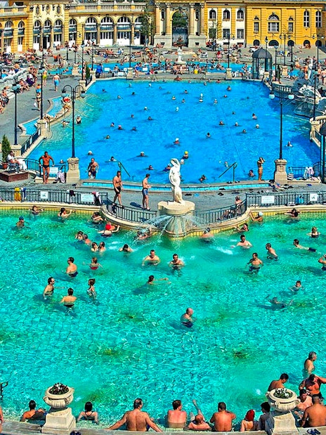 Outdoor pool at Széchenyi Thermal Bath, Budapest, with people swimming and relaxing.