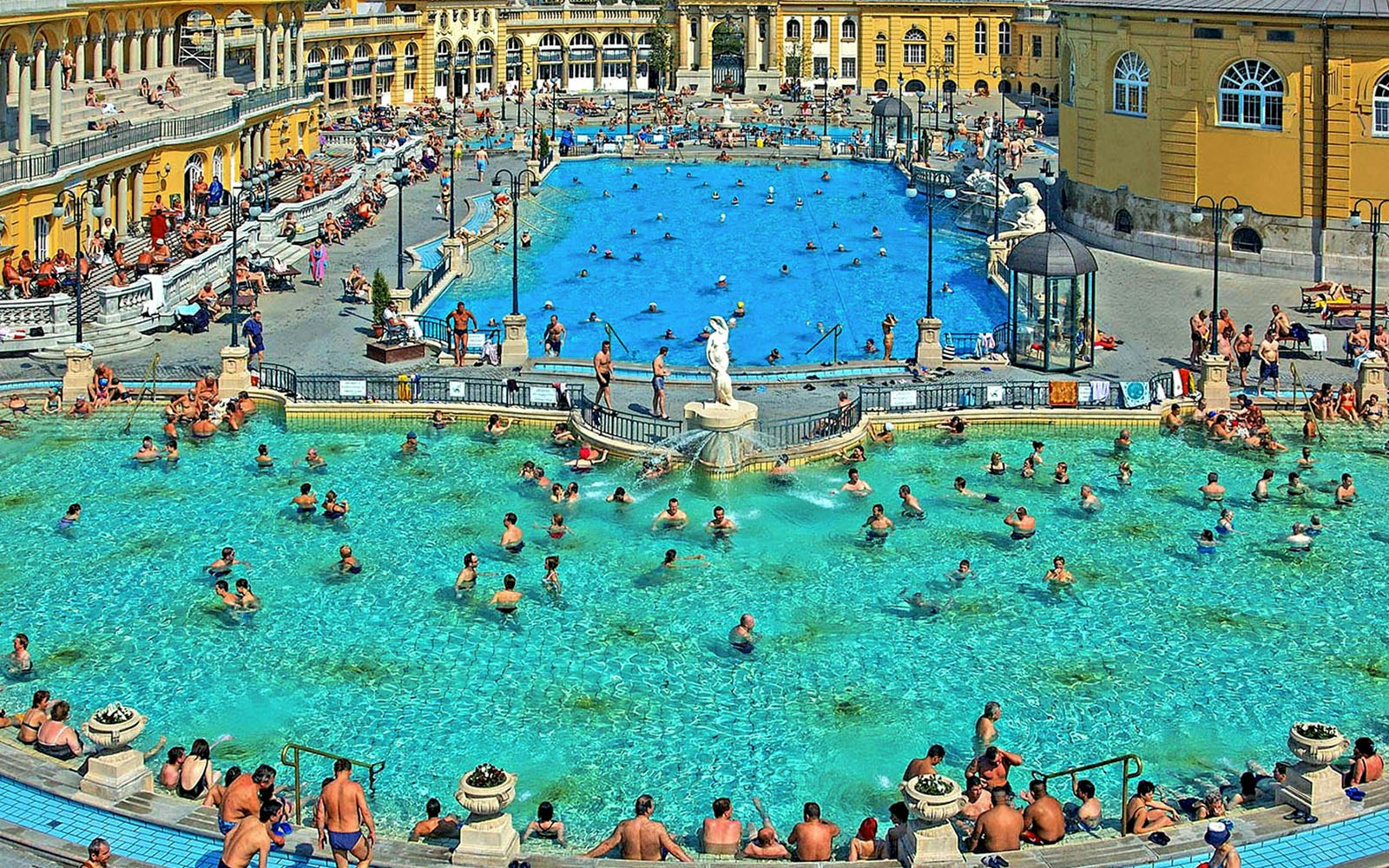 Outdoor pool at Széchenyi Thermal Bath, Budapest, with people swimming and relaxing.