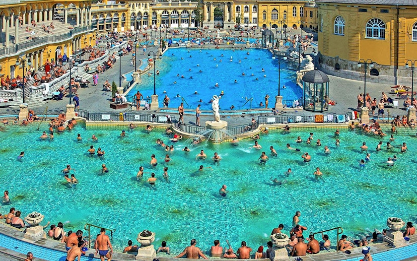 Outdoor pool at Széchenyi Thermal Bath, Budapest, with people swimming and relaxing.