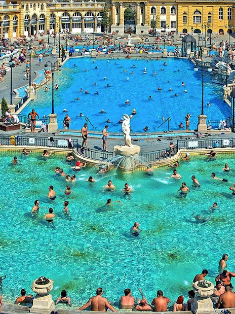 Outdoor pool at Széchenyi Thermal Bath, Budapest, with people swimming and relaxing.