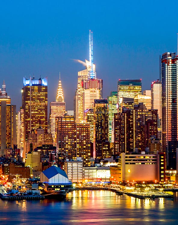 Manhattan midtown skyline with illuminated buildings at dusk, New York City.