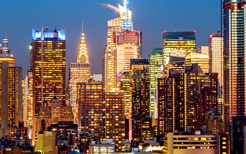 Manhattan midtown skyline with illuminated buildings at dusk, New York City.