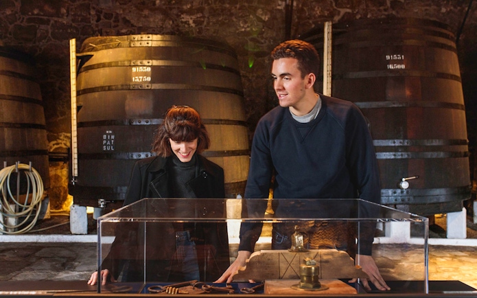 Visitor exploring Fonseca Port Wine Cellars with large barrels in the background.