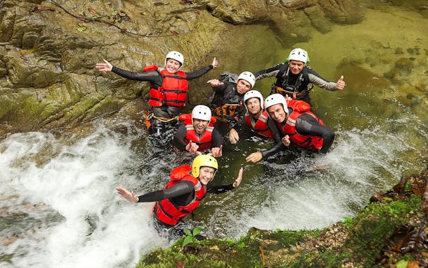 Group enjoying water canyoning in Braga, wearing helmets and life vests in a rocky stream.
