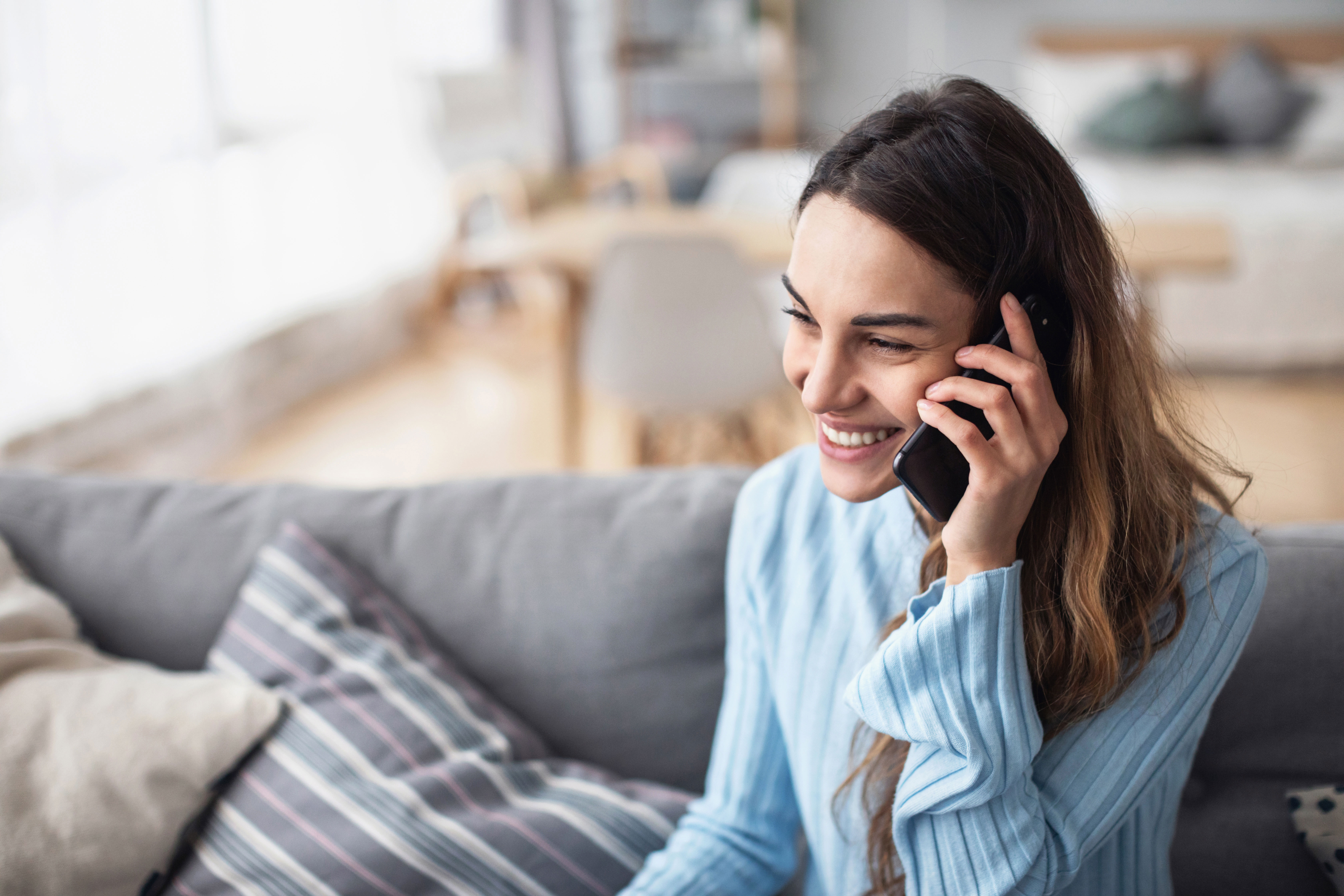 Attractive smiling woman talking on the phone at home.