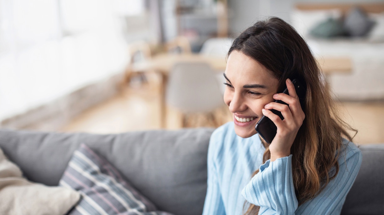 Attractive smiling woman talking on the phone at home.