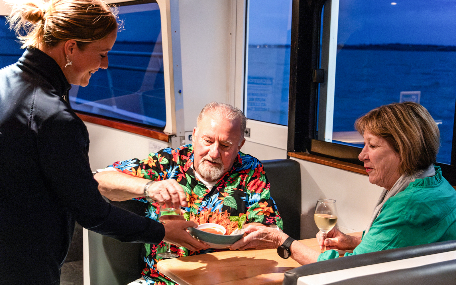 Server offering seafood dish to couple on Phillip Island sunset cruise.